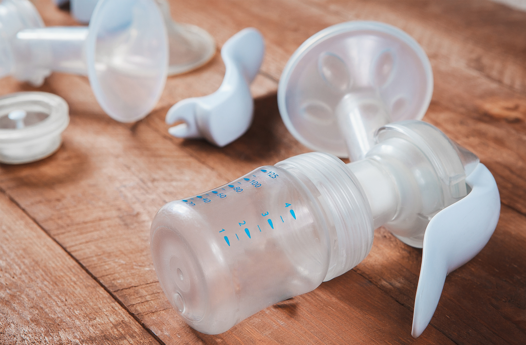 image of different breast pump parts on a brown wooden table